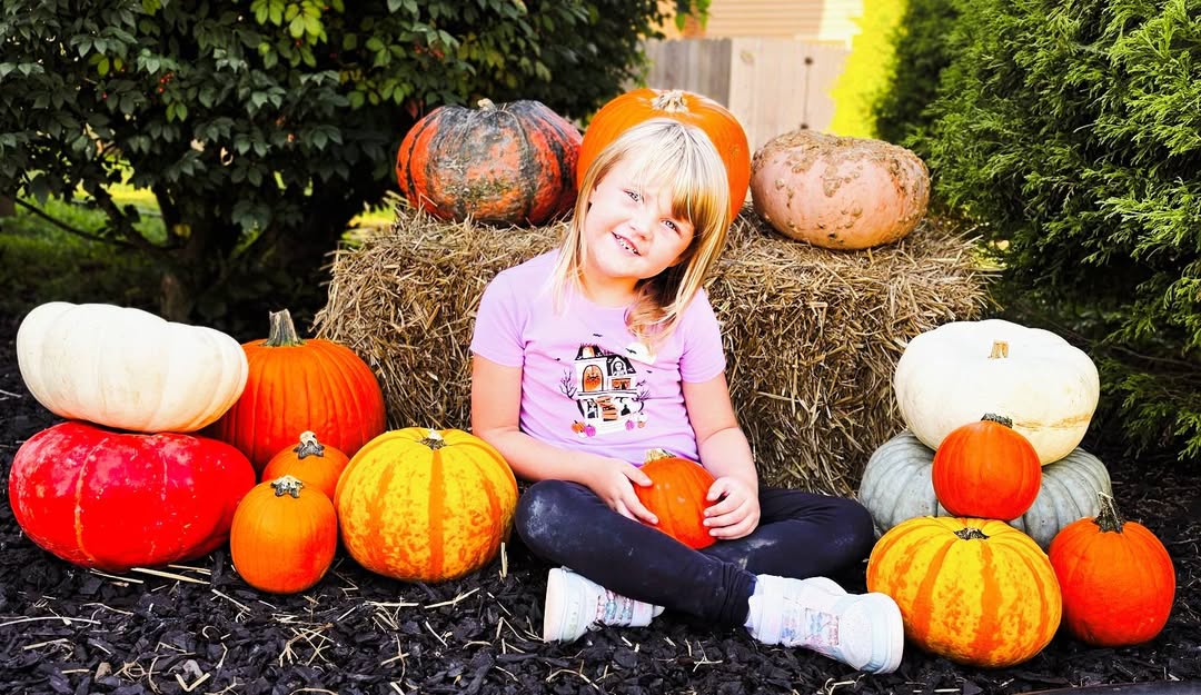 Student sitting among pumpkins